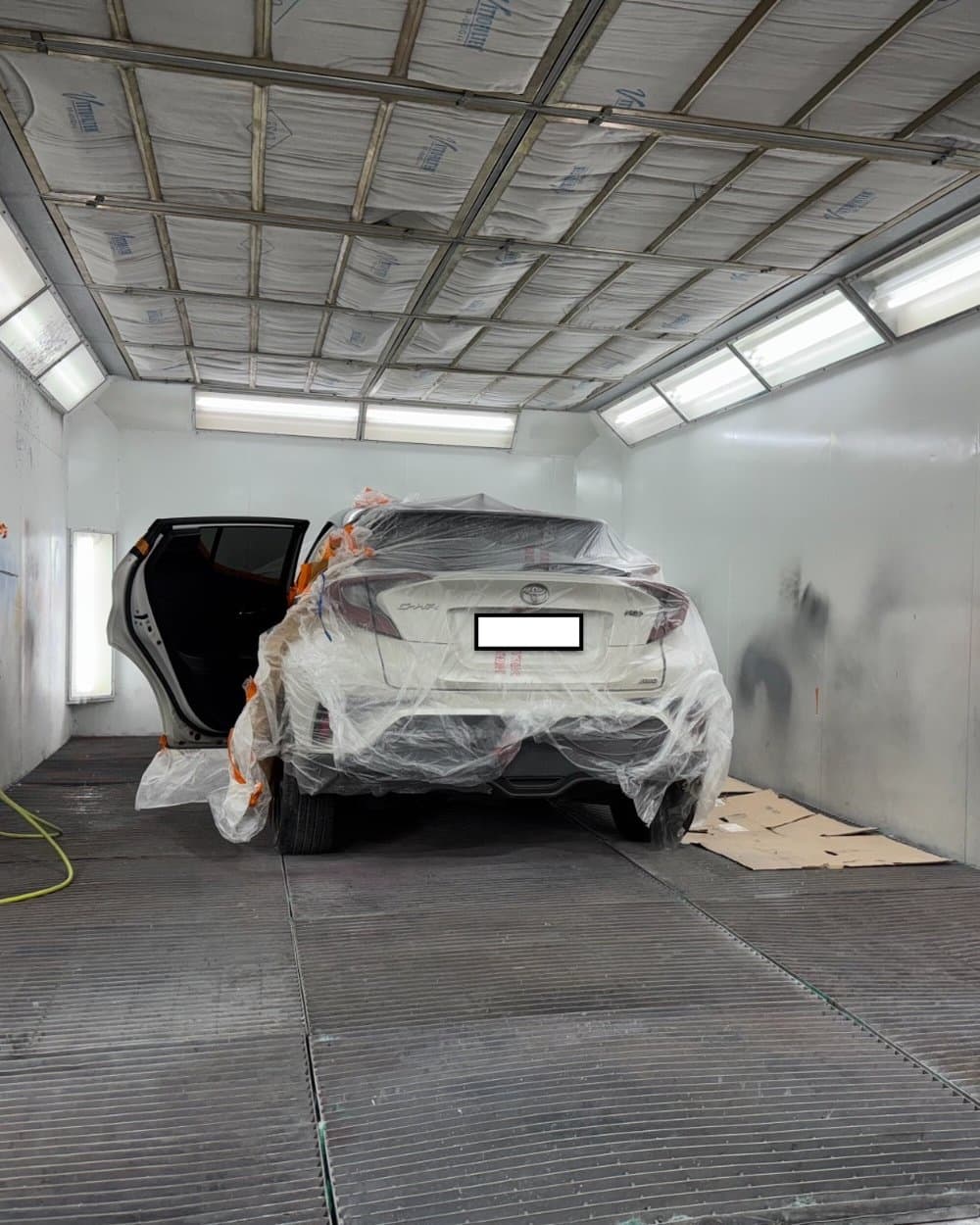 Car masked up inside a lit spray booth